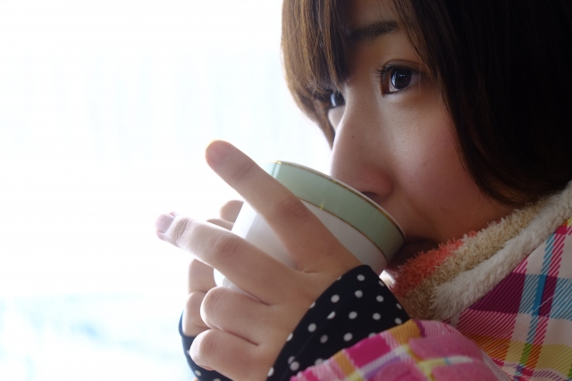 お茶を飲んで温まっている女性のイメージ画像です。